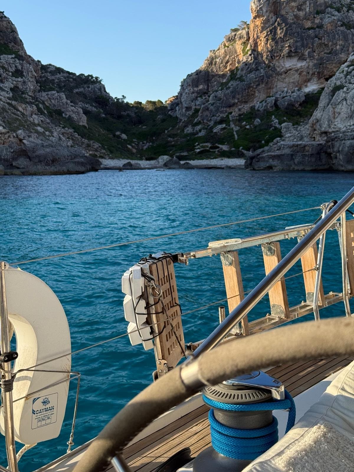Cala de aguas turquesas entre acantilados, vista desde la cubierta de un velero