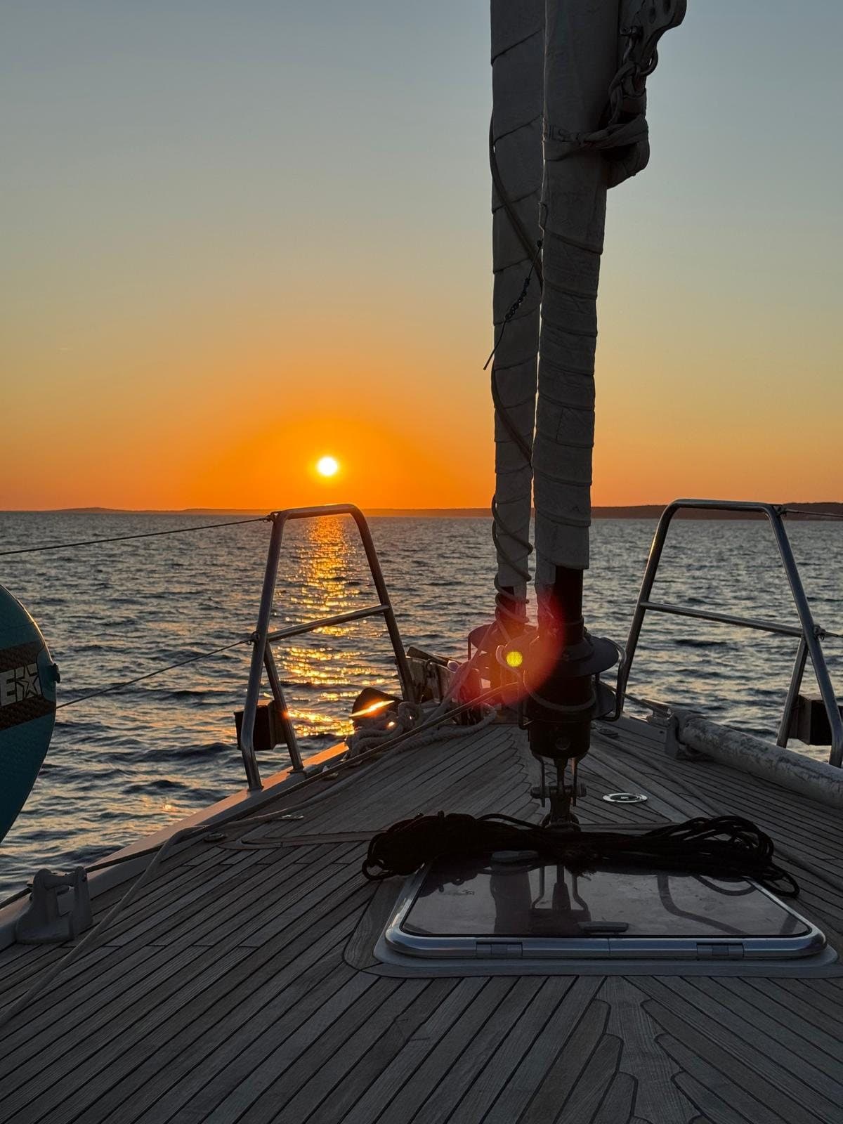 Proa de madera de un velero con el sol poniéndose en el horizonte